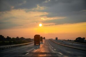 trucks driving on big road into the sunset