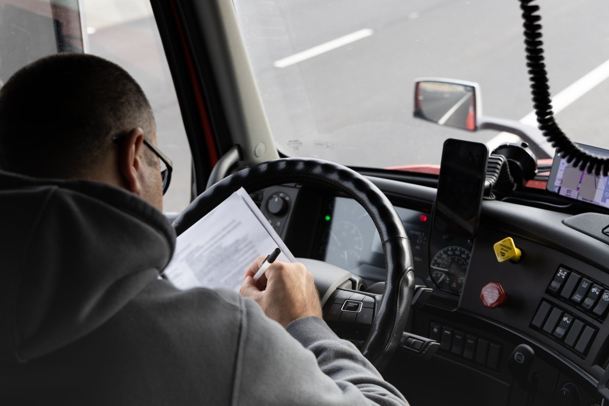 Driver reviews documents while operating truck on highway in Pleasant Grove California