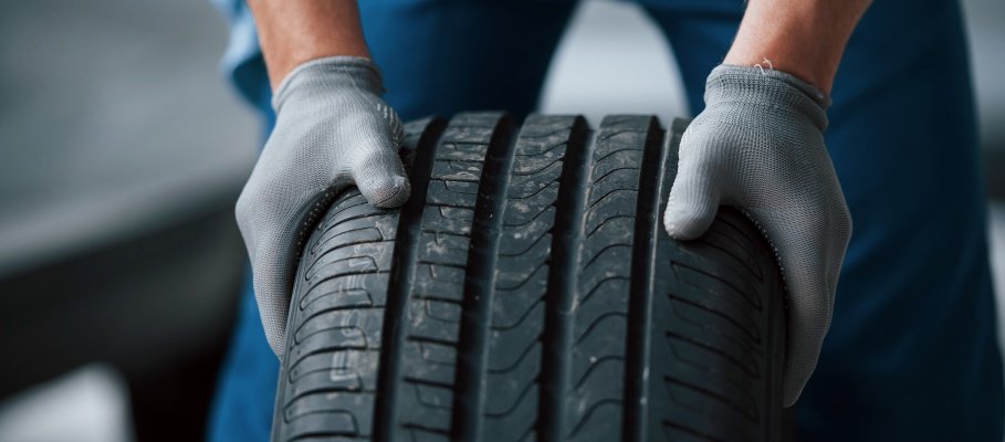 Dirt on the wheel. Mechanic holding a tire at the repair garage. Replacement of winter and summer tires