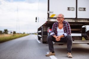 Senior man sitting on the back side of his truck.