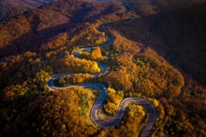 An aerial view of the winding road through a high mountain pass, passing through dense forest