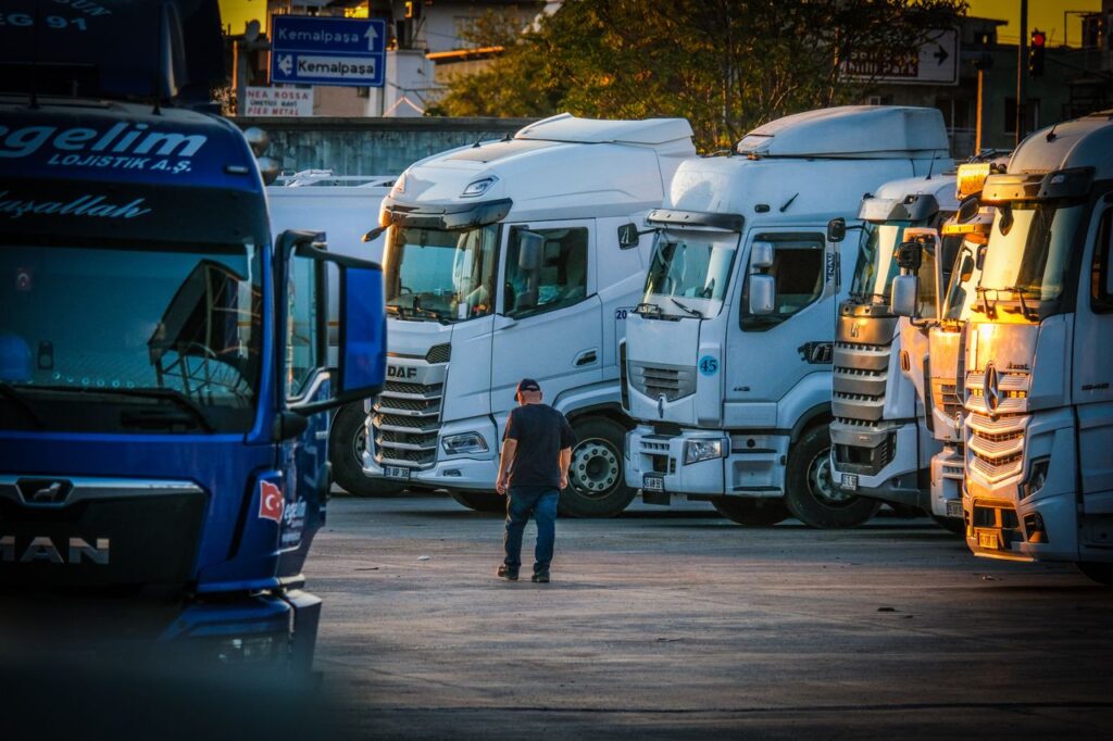 Man walking through a lot of parked semi-trucks while shopping for a used commercial vehicle loan