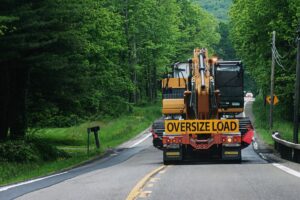 A truck carrying an oversize load, taking up 2 lanes of rural road.