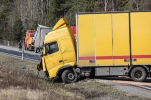 yellow truck dented and off road from an accident