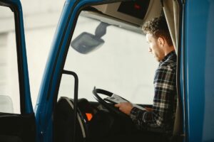 Man sitting behind wheel of a truck and reading papers
