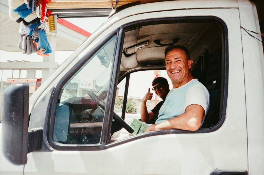 Truck driver giving a thumbs up from the cab of his truck at a fuel stop