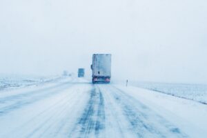 Freight transportation truck on the road in snow storm blizzard, bad weather conditions for transportation event, selective focus
