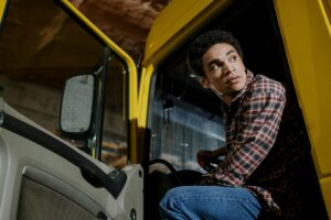 young truck driver in a yellow truck with the door open