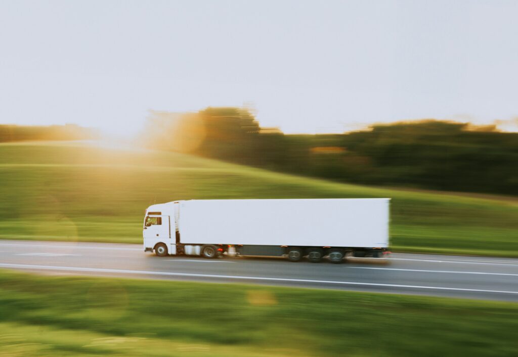 white truck driving along a road next to grassy areas. Motion shot. 