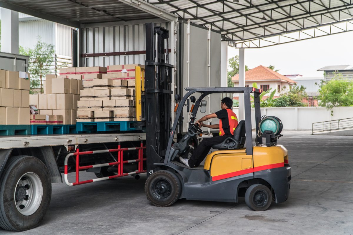 Worker loading pallet with a forklift into a truck