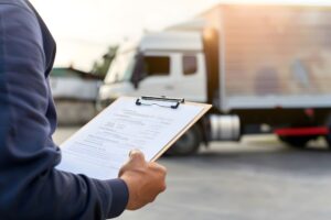 person holding a clipboard near a semi truck