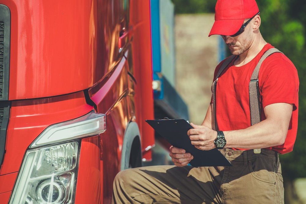 Semi Truck Driver Checks Paperwork During Vehicle Inspection at Site