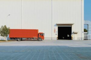 red commercial truck parked next to warehouse