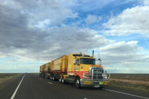 yellow commercial truck driving on open road