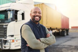Delivery, container and happy truck driver moving industry cargo and freight at a shipping supply chain or warehouse. Smile, industrial and black man ready to transport ecommerce trade goods or stock.