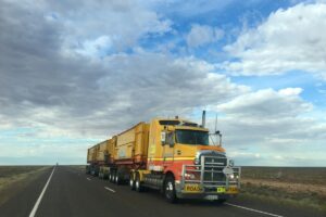 Big yellow truck on open road with cloudy skies