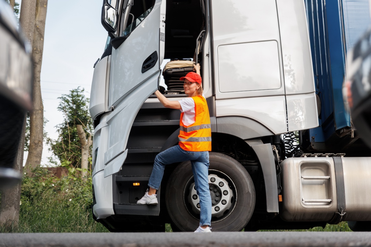 Portrait young adult happy smiling woman climbing cabin heavy truck driver cargo vehicle. Female person girl professional job career working driving freight engine lorry. Logistics industry