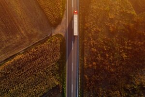 Truck on the road in sunset, top view of single transportation vehicle with trailer from drone pov