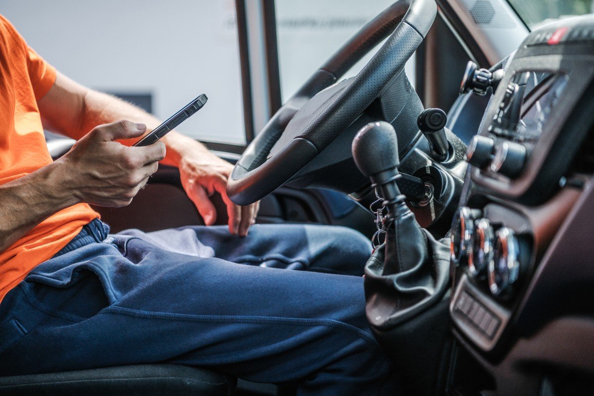 Delivery Truck Driver Browsing Internet Using His Smartphone