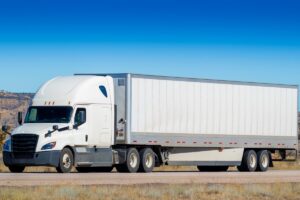 An Eighteen wheel big rig tractor trailer on highway. Trucking industry