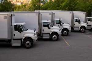 Many cargo trucks in straight row at parking lot
