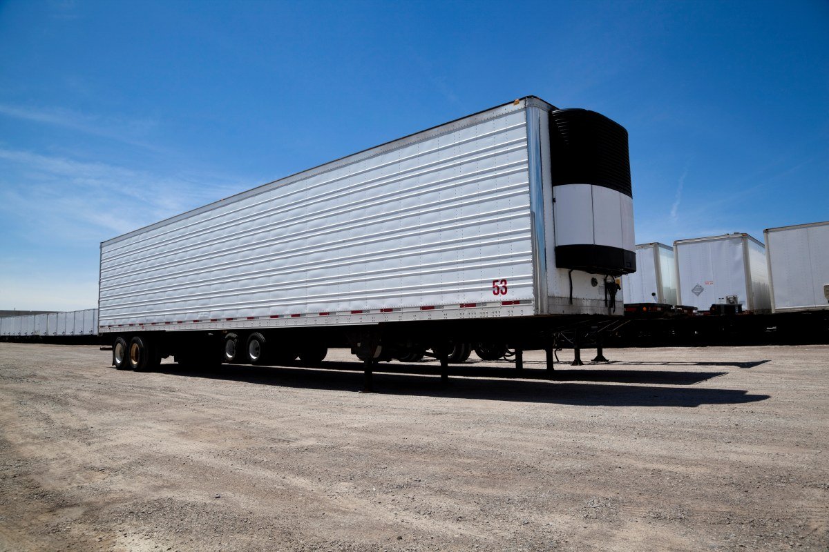 Transport truck trailer sitting in yard with a row of trailers behind it