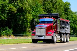 heavy duty red dump truck going down the highway.