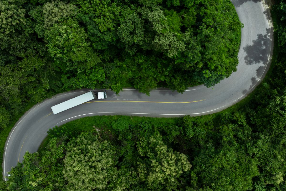 Aerial view semi truck trailer cargo on mountain curve road, Semi truck trailer cargo business logistic transportation on green forest road curve, Semi truck delivery asphalt road green forest tree.