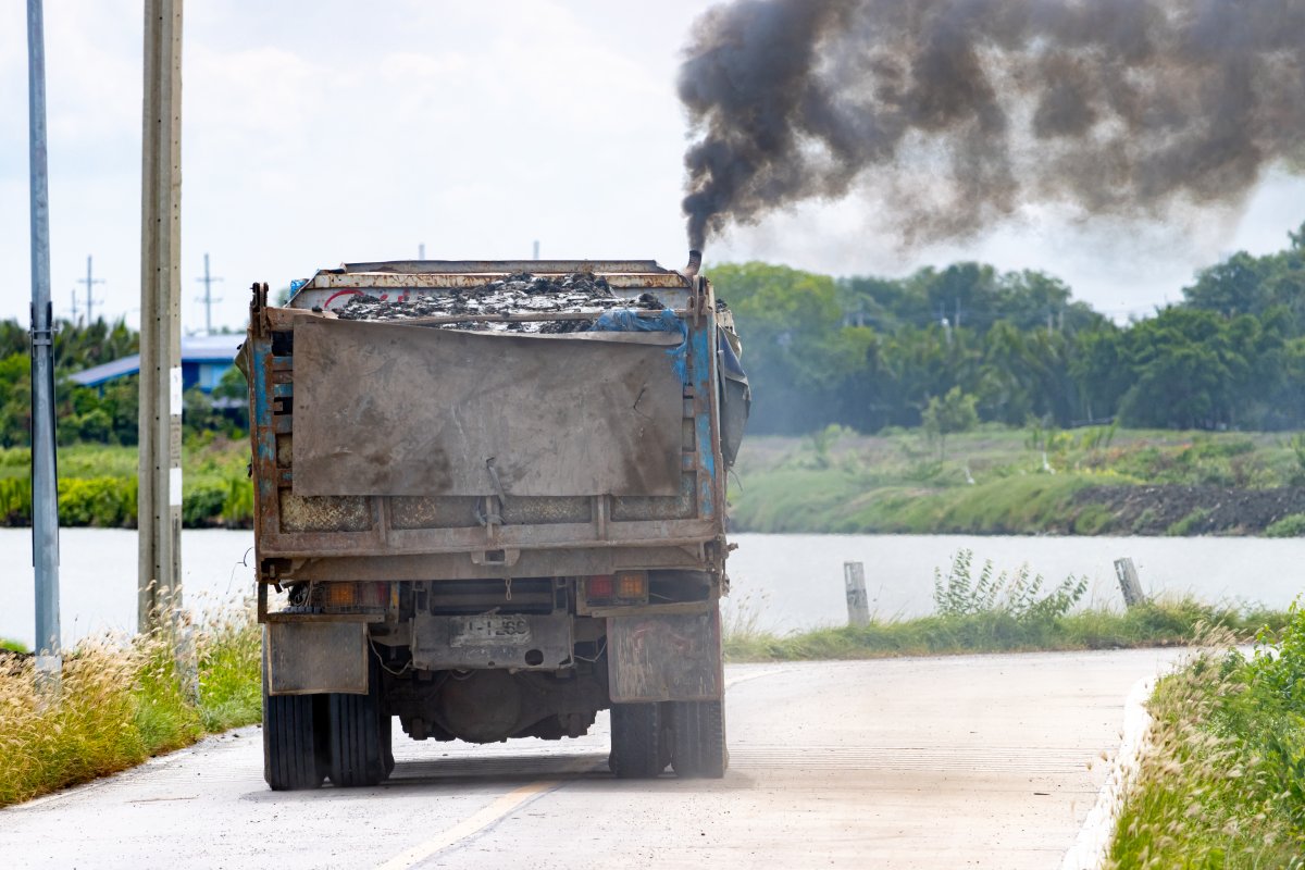A loaded truck ride on the road with thick black smoke from the exhaust