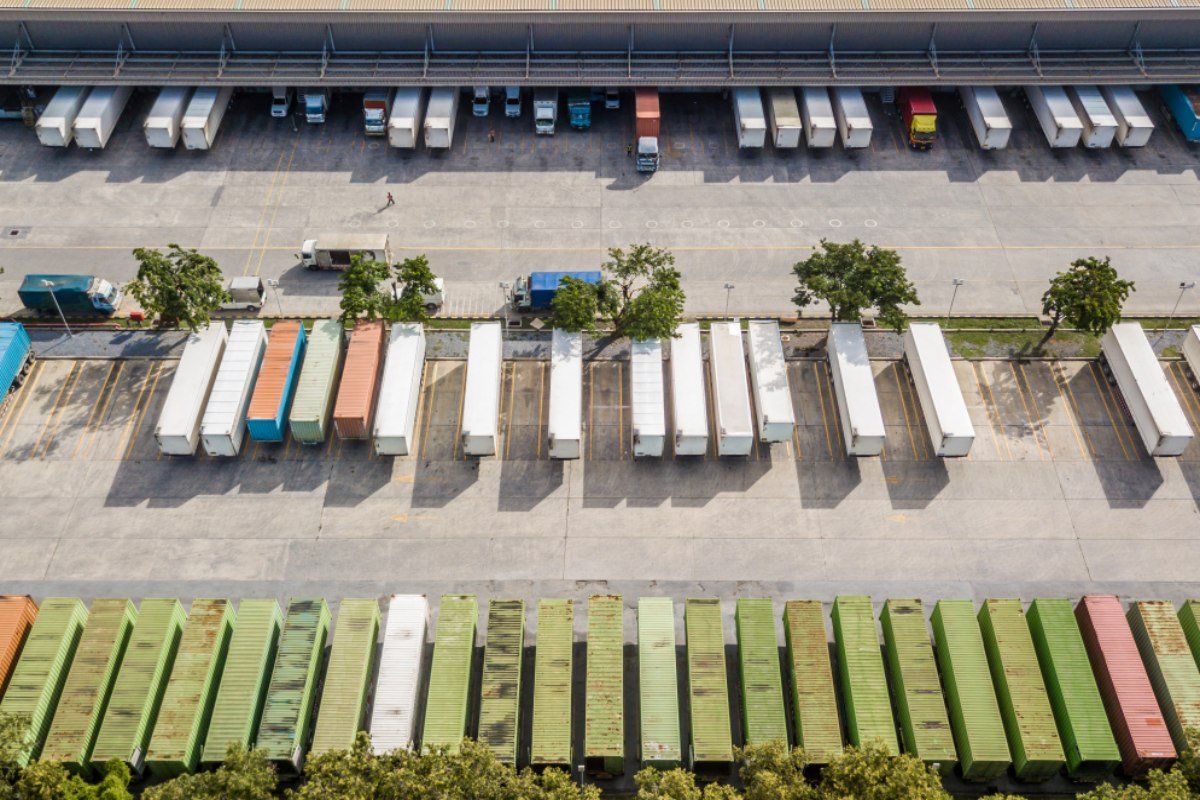Aerial top view of truck and cargo trailer unloading in logostics center.