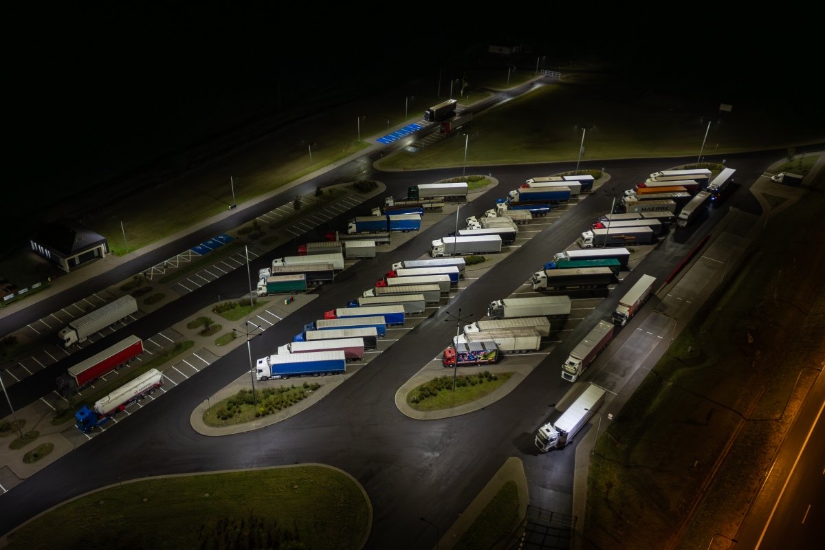 Aerial view of a brightly lit truck stop at night, full of semi-trucks parked for the evening.