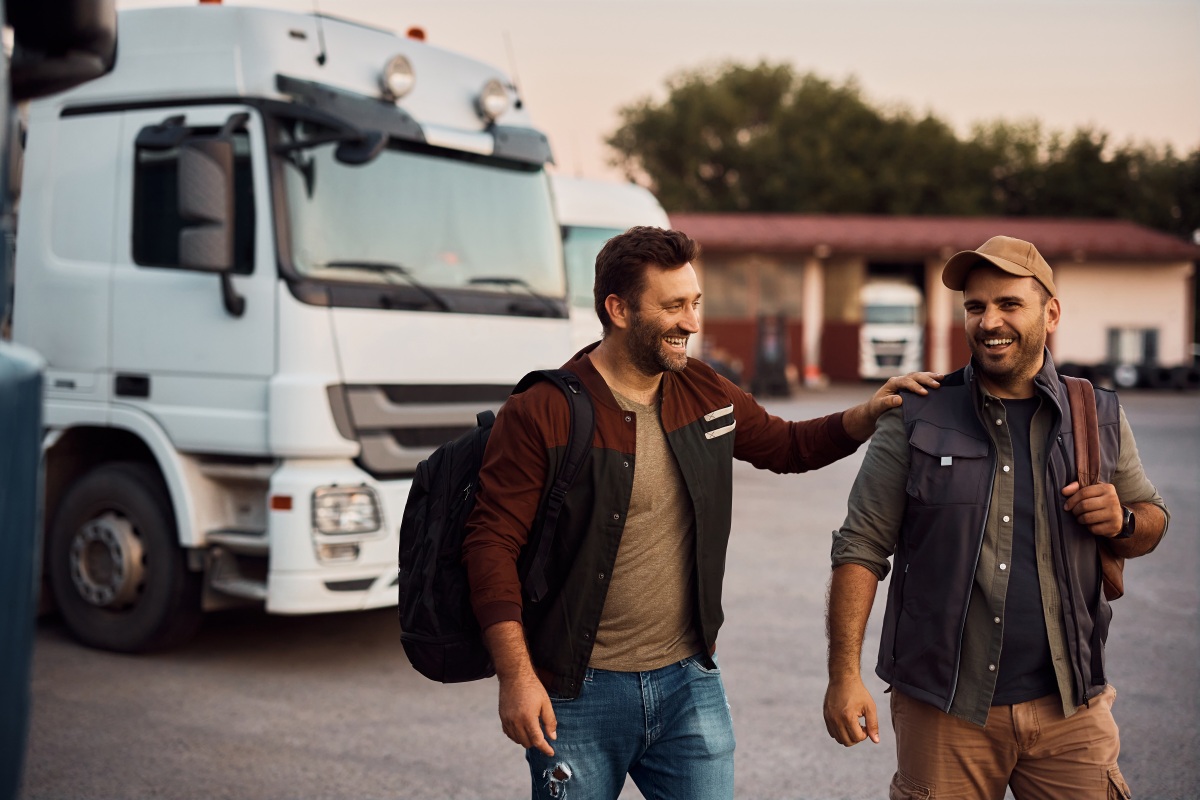 Cheerful truck drivers have fun on parking lot.
