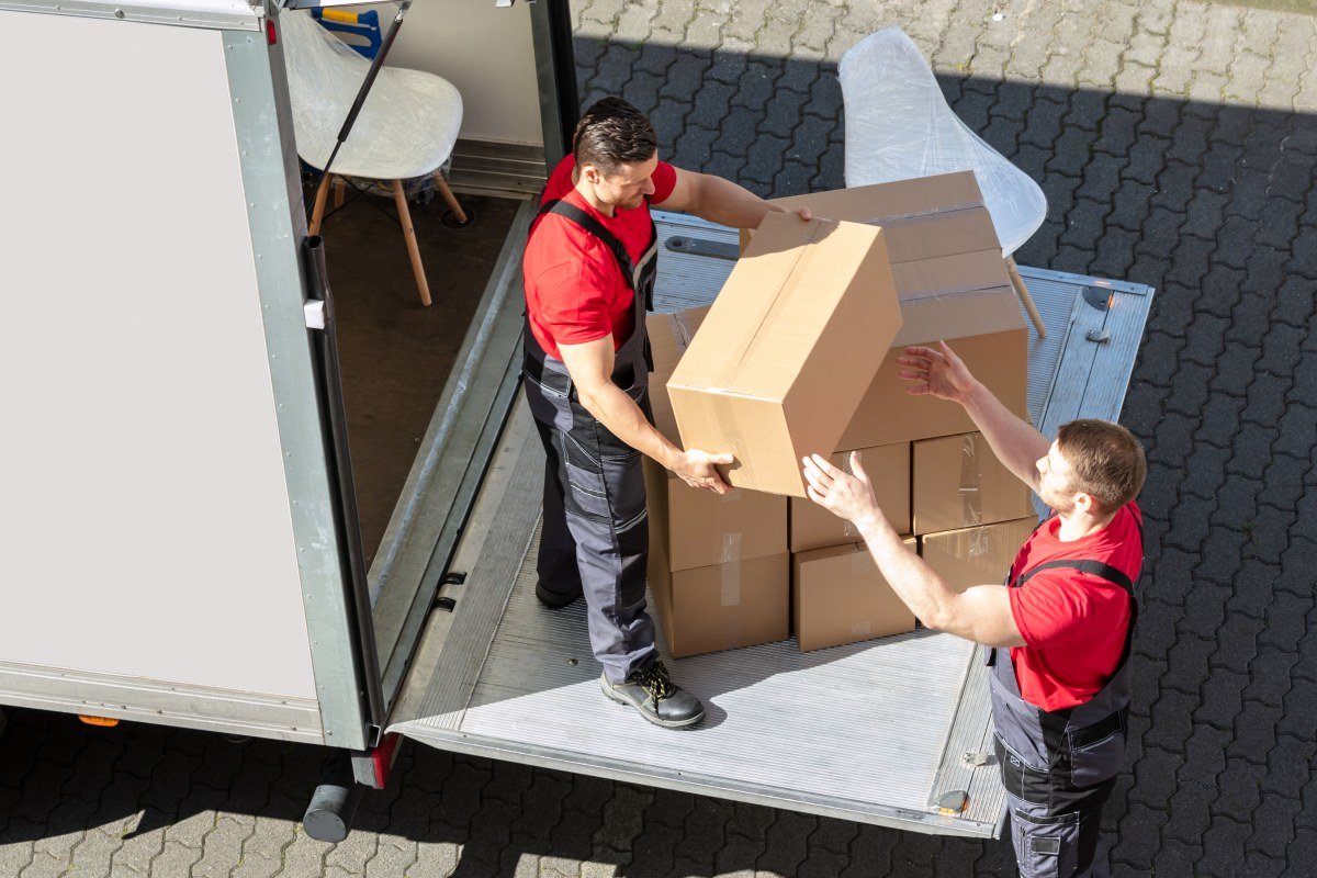 Male Movers Unloading The Cardboard Boxes Form Truck