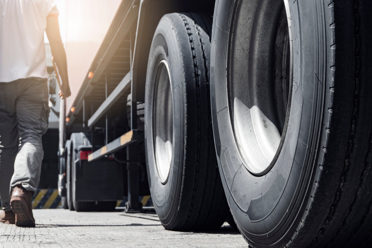 Closeup a truck wheels and a truck driver holding clipboard insp