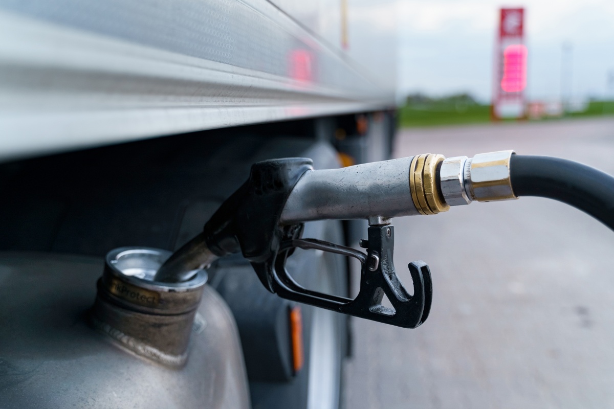A close-up of a gas station gun inserted into the fuel tank.