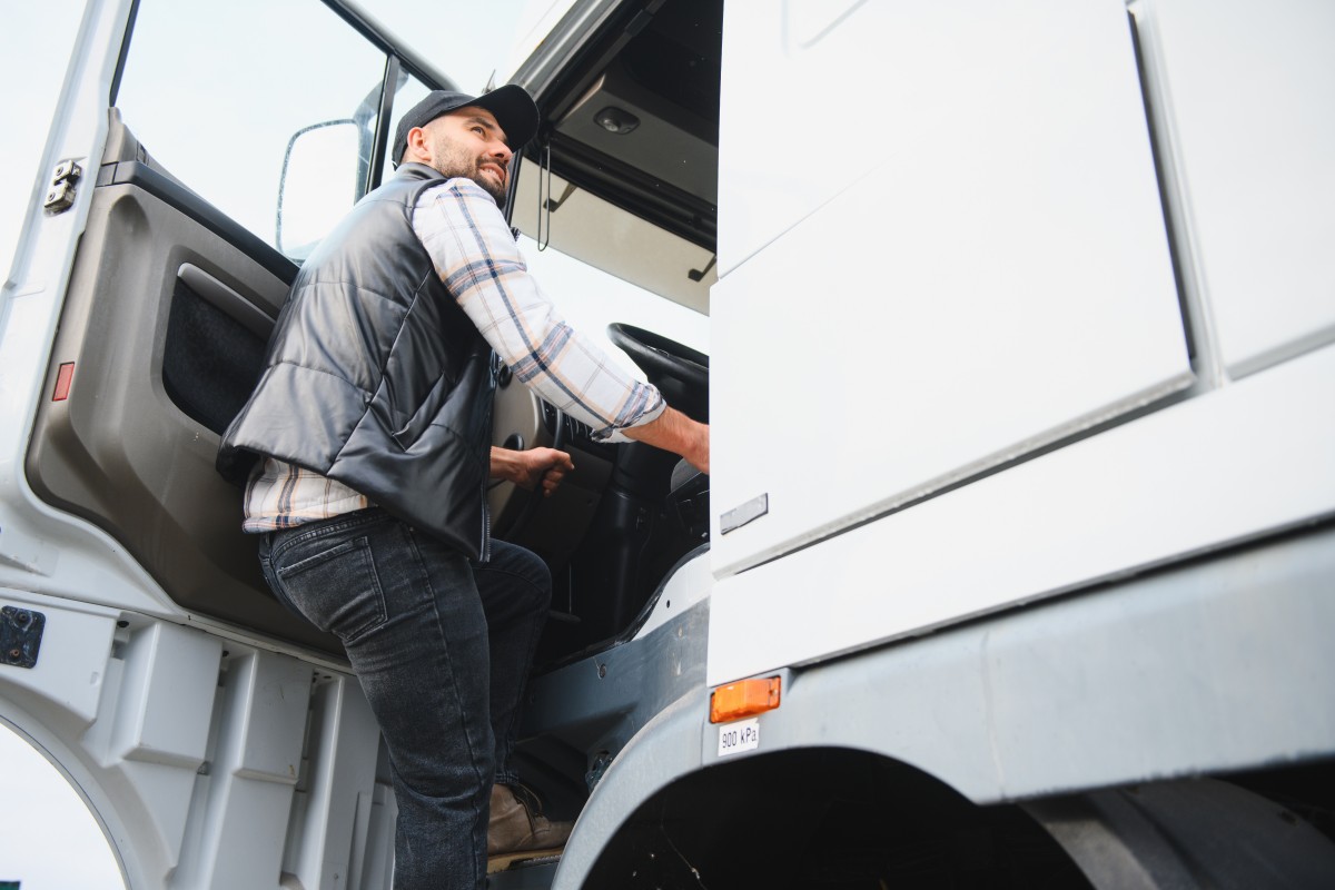 Professional truck driver entering cabin of heavy vehicle