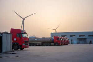 Red truck fleet parked at wind power plant industrial area during sunset