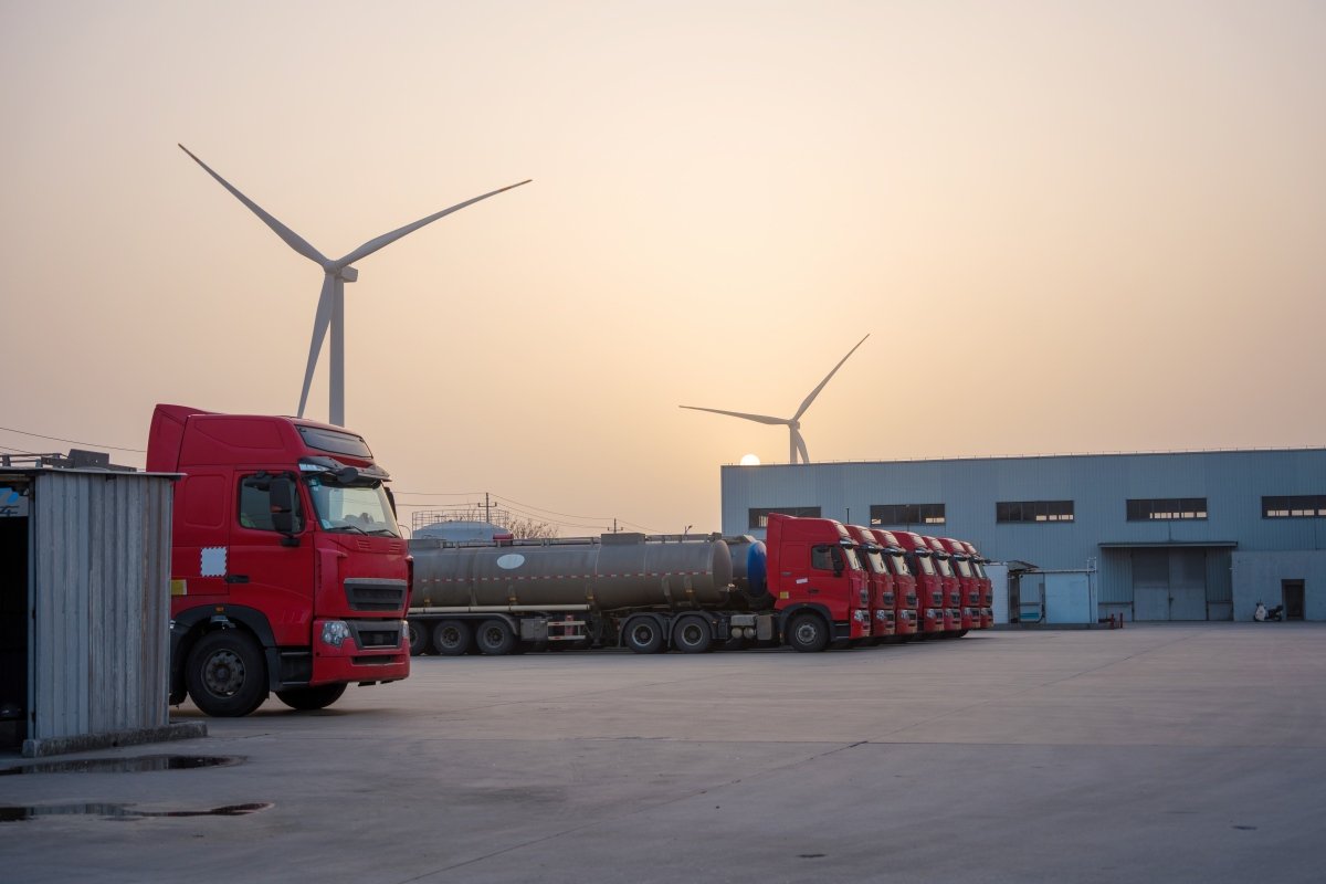 Red truck fleet parked at wind power plant industrial area during sunset