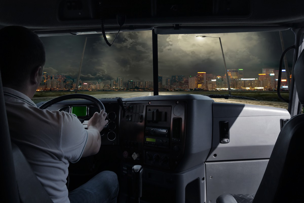 the driver is a truck with a load in the night city. business tr