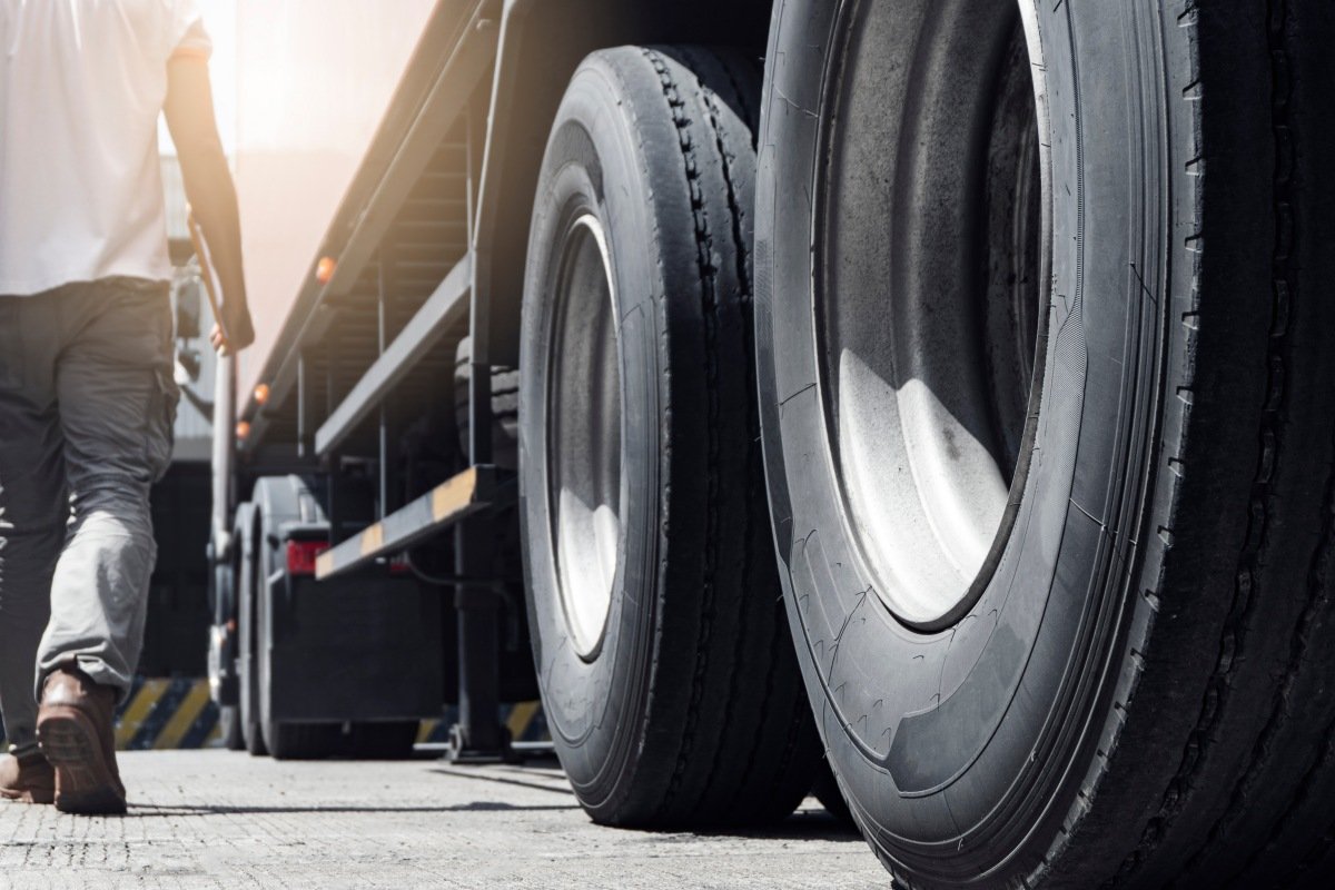 Closeup a truck wheels and a truck driver holding clipboard insp