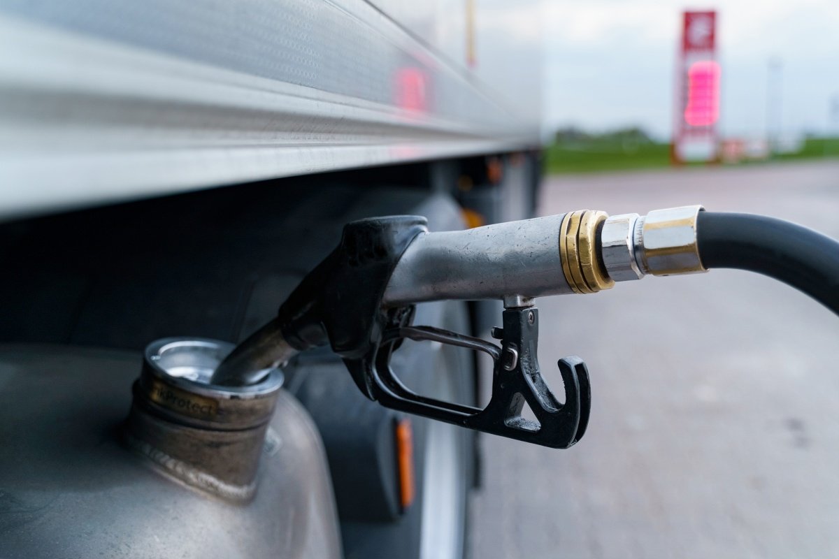 A close-up of a gas station gun inserted into the fuel tank.