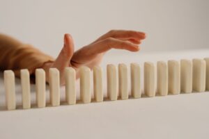 Hand stopping a row of dominoes from falling, representing proactive fleet risk management