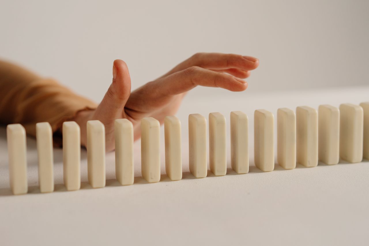 Hand stopping a row of dominoes from falling, representing proactive fleet risk management