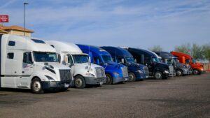 A lineup of semi trucks in different colors parked at a truck stop, representing the range of vehicles to evaluate when deciding to replace fleet vehicles