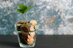 Coins in a glass jar with a small plant sprouting from them, symbolizing how small changes can grow into real savings on fleet costs