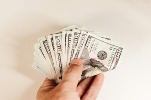 Hand holding a fan of hundred-dollar bills for a semi truck loan down payment