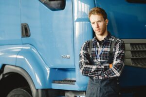 Owner-operator standing with arms crossed in front of his semi truck