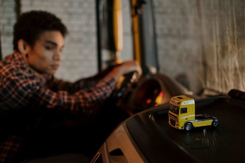 Truck driver behind the wheel with a model semi truck on the dashboard