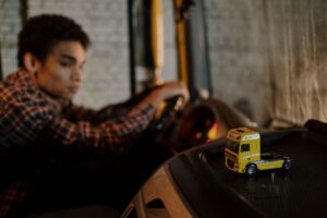 Truck driver behind the wheel with a model semi truck on the dashboard