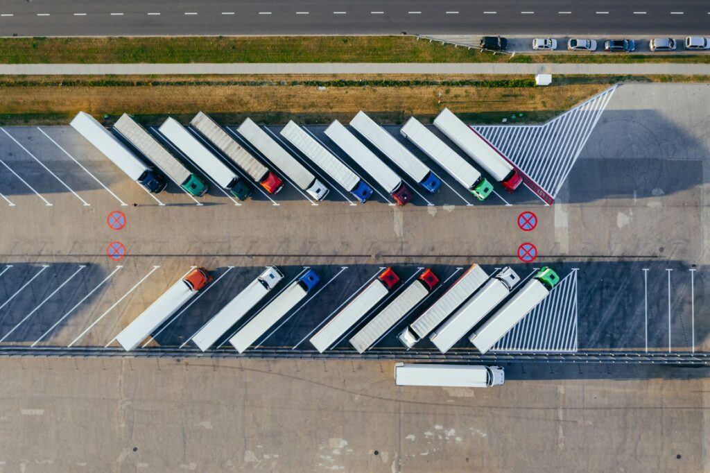 Aerial view of semi trucks with white trailers parked in angled rows at a freight lot, the kind of equipment that can qualify for a Section 179 deduction